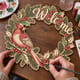 Hands painting the Welcome wreath with a cardinal on a holly branch at a craft table