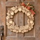 Unpainted wooden Hello Fall acorn wreath hanging on a front door