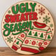 Painted round Ugly Sweater Season sign standing on a wooden table