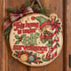Painted round This Home Is Under Elf Surveillance sign hanging on a wooden front door