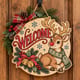 Painted round reindeer Welcome sign with jingle bells hanging on a wooden front door