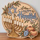 Painted round Happy Hanukkah sign with a menorah and dreidel standing on a wooden table