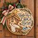 Painted round Unto Us a Child Is Born sign with baby Jesus in a manger hanging on a wooden front door