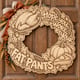 Unpainted wooden Hope You Wore Your Fat Pants Thanksgiving wreath hanging on a front door