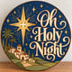 Painted round Oh Holy Night sign with the Star of Bethlehem standing on a wooden table