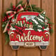 Painted red truck Christmas welcome door hanger hanging on a wooden front door