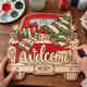 Hands painting the red truck Christmas welcome door hanger at a craft table