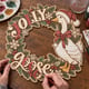 Hands painting the Jolly Goose Christmas wreath with a goose in a Santa hat at a craft table