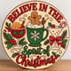 Painted round Believe in the Spirit of Christmas cocktail sign standing on a wooden table