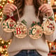 Person holding four painted personalized alphabet Christmas ornaments