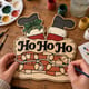Hands painting the Ho Ho Ho Santa chimney door hanger at a craft table