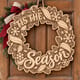 Unpainted wooden Tis the Season wreath with swirling ribbons and snowflakes hanging on a front door