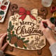 Hands painting the Merry Christmas sled door hanger at a craft table