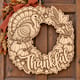 Unpainted wooden Thankful Thanksgiving wreath with a turkey and pumpkins hanging on a front door