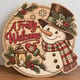 Painted round A Frosty Welcome snowman sign standing on a wooden table