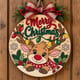 Painted round reindeer Merry Christmas sign with string lights hanging on a wooden front door