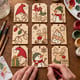 Hands painting a set of nine wooden Christmas gift tags