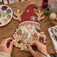 Hands painting the Christmas gnome door hanger with reindeer antlers at a craft table