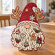 Painted Christmas gnome door hanger with reindeer antlers standing on a wooden table