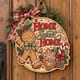 Painted round gingerbread man Home Sweet Home sign hanging on a wooden front door