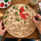 Hands painting the round cardinal memorial sign reading I'm always with you at a craft table