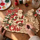 Hands painting the Merry Christmas door hanger with Santa, a snowman, a reindeer and hanging charms at a craft table