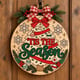Painted round Tis the Season Christmas tree sign hanging on a wooden front door