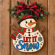 Painted Let It Snow snowman door hanger hanging on a wooden front door